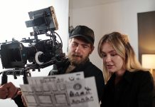 Bearded videographer and his blond female assistant discussing documents