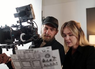 Bearded videographer and his blond female assistant discussing documents